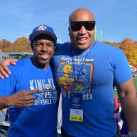 Two black alumni smile for a photo in Lubbers Stadium.